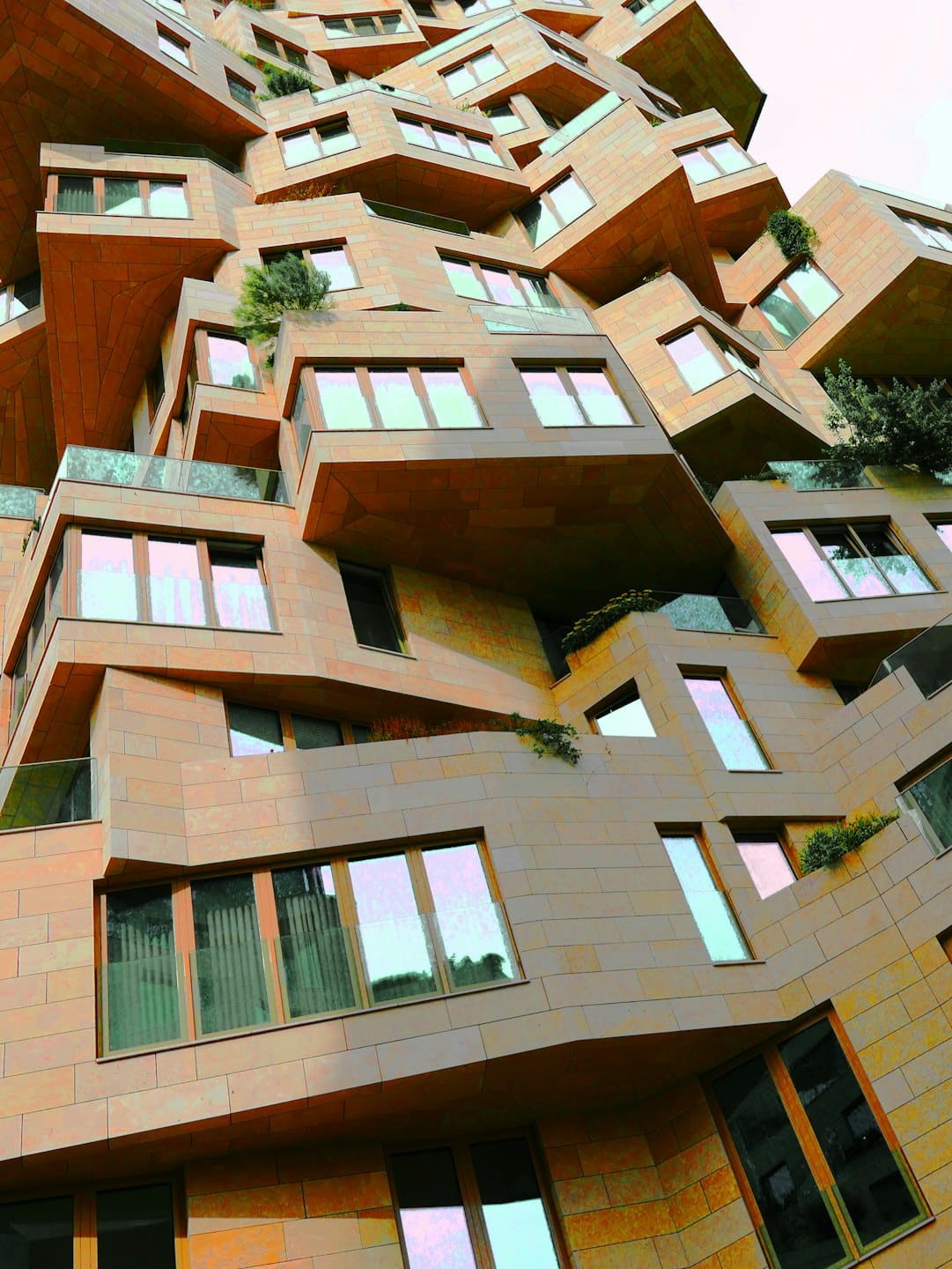 Edificio moderno in pietra con finestre in vetro e fioriere esterne.