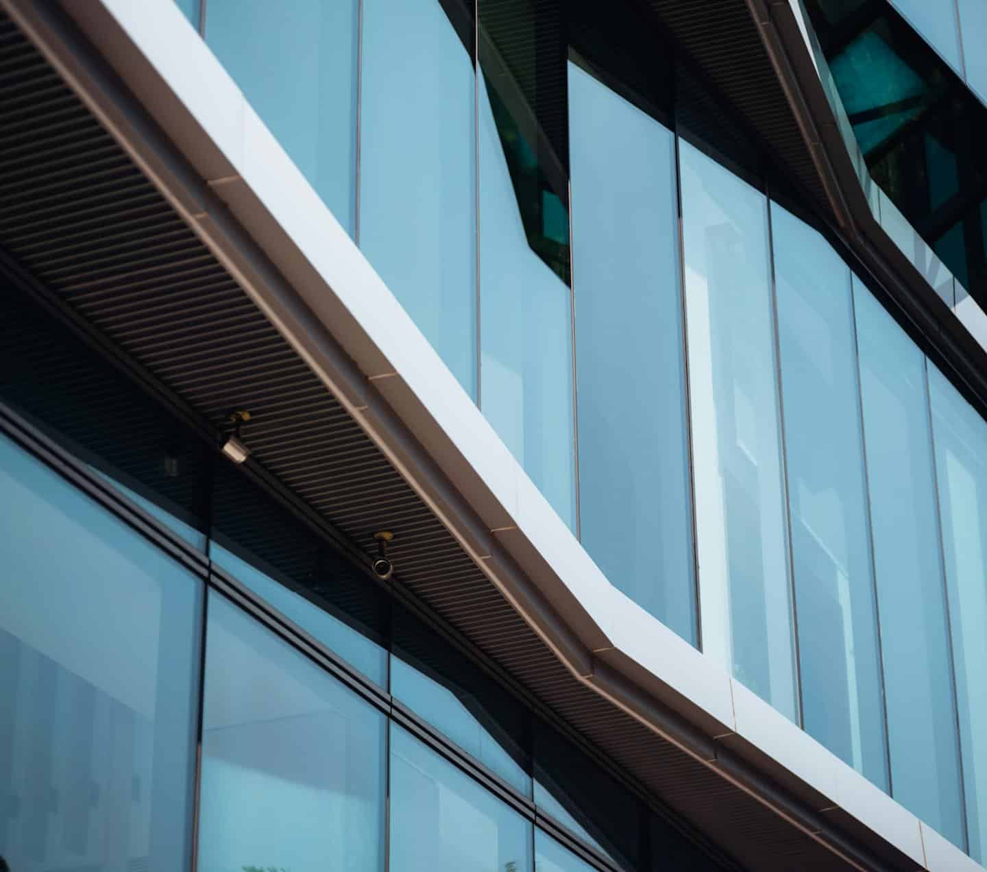 Facciata moderna di un edificio in vetro e metallo con riflessi blu.